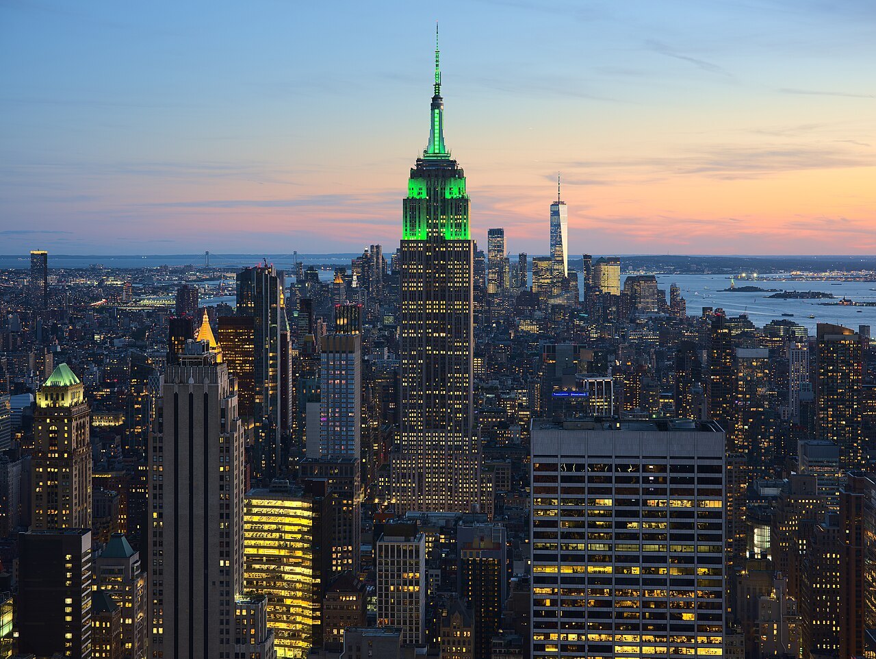 View of the Empire State Building in New York City from the Top of the Rock at 30 Rockefeller Plaza during sunset. The tower was illuminated in green in honor of Climate Week NYC