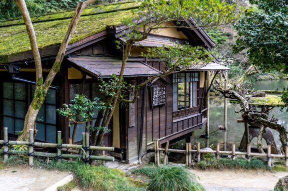 A traditional Japanese tea house surrounded by lush greenery and situated beside a serene lake, exuding tranquility.