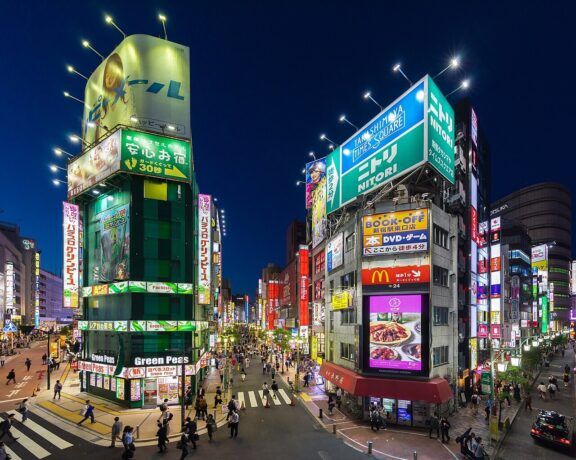 Facades of Green Peas pachisuro parlor and Naganoya restaurant, colorful neon street signs at blue hour, view from Koshu-kaido Avenue, Shinjuku station JR East. Entertainment district in Shinjuku, Tokyo, Japan.
