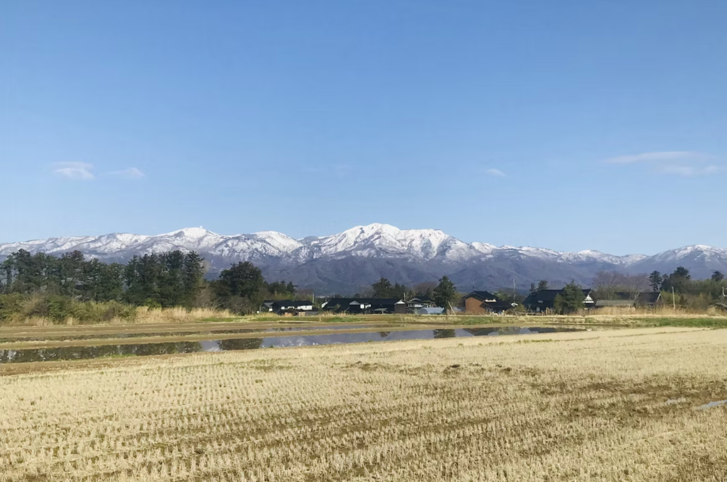 A rural landscape overlooking snow-capped mountains